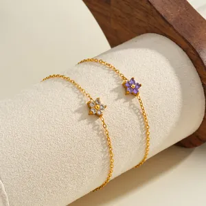 Close-up detail of dainty flower-shaped bracelets with purple and white zirconias