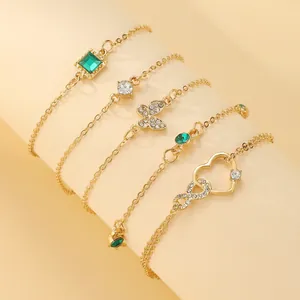 Detailed view of layered Bohemian gold anklet set with emerald stones and charms
