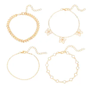Close-up detail of four gold anklets set featuring leaf, butterfly, and crystal designs.