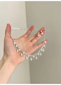 Nahaufnahme eines Vintage-Schmucksets mit Perlen und Strasssteinen in der Hand