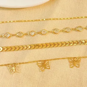 Close-up of four Bohemian style gold anklets with butterfly and crystal details.