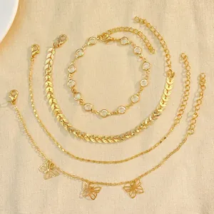 Detailed close-up view of a four-piece bohemian gold anklet set with butterflies and leaves.