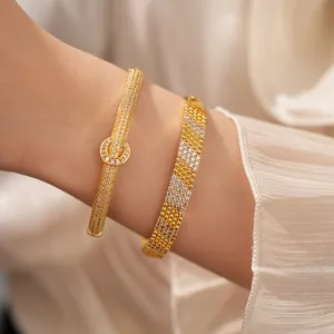 Λεπτομερής προβολή επίχρυσων βραχιολιών 18K με ζιργκόν στον καρπό του χεριού