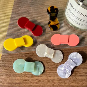 Elegant multi-color acetate hair clips in geometric shapes displayed on a wooden surface