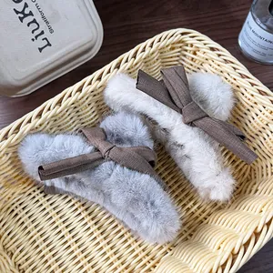 Plush flower shark clips in beige and grey with bow detail in a woven basket