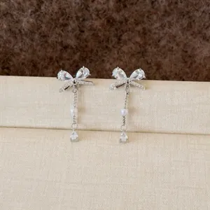 Detail macro shot of elegant silver bow earrings with sparkling zircon tassels and white pearls