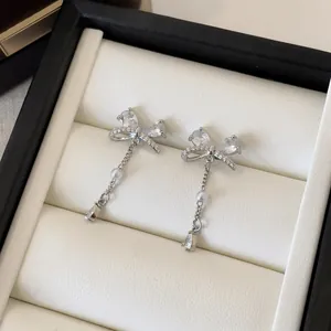 Close-up of elegant bow earrings with zircon tassels and delicate pearl detail