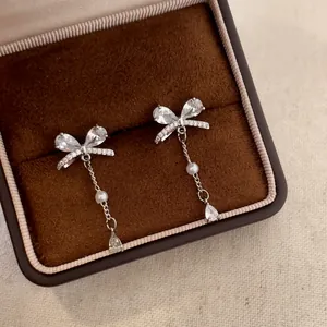 Elegant silver zircon bow-knot tassel earrings with pearl accents in a brown gift box