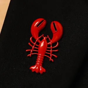 Detail view of a vibrant red enamel lobster brooch pinned on black textured fabric