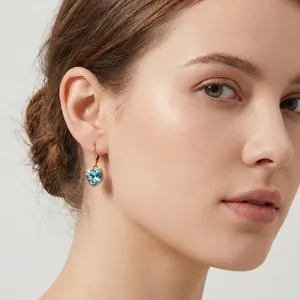 Detailansicht eines eleganten hellblauen Herz-Kristall-Ohrrings am Ohr eines Models