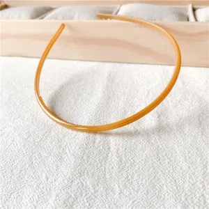 Detail of amber thin headband with non-slip teeth on textured white background