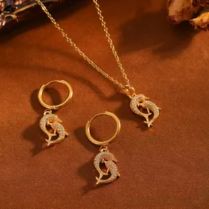Detailansicht eines goldenen Delfin-Schmucksets mit Pavé-Halskette und Creolen-Ohrringen.