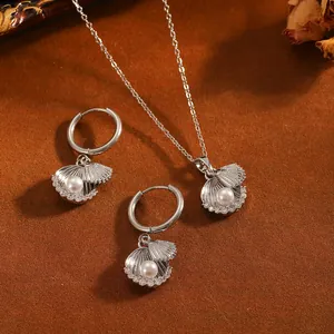 Detailansicht des silbernen Muschel-Perlen-Schmucksets auf braunem Hintergrund