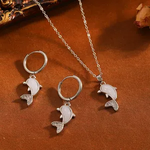 Nahaufnahme von Delfinanhängern mit Muscheleinlage und Pavé-Steinen in einem Schmuckset