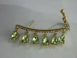 Close-up of gold ear cuff with white zircons and six light green teardrop gemstones