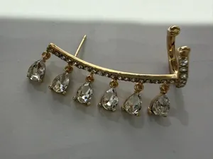 Detailed shot of golden ear cuff with zircons and hanging teardrop crystal tassels