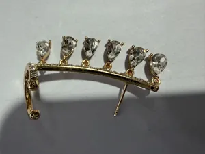 Detail view of golden water drop tassel crawler earring with teardrop zircon stones