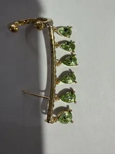 Detail of gold water drop tassel earrings with green zircon stones and ear cuff clip