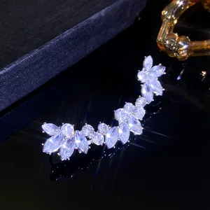 Macro shot of silver zircon leaf-shaped ear cuff on high-reflective black surface