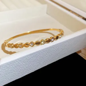 Vue rapprochée d'un bracelet jonc en acier doré avec des cœurs et zircons étincelants