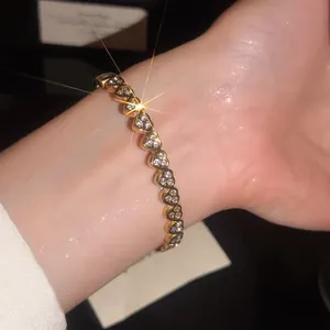 Gros plan d'un bracelet en acier inoxydable de luxe avec zircons étincelants en cœur.