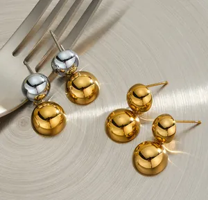 Primo piano di orecchini minimalisti a sfera in acciaio inossidabile oro e argento