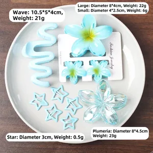 Ensemble de pinces à cheveux bleues ondulées et fleurs de frangipanier sur plateau décoré