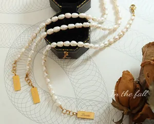Collana di perle barocche con ciondolo Love dorato e chiusura su sfondo vintage