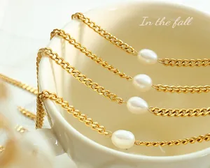 Detailed macro view of golden Cuban link chains featuring elegant oval freshwater pearls
