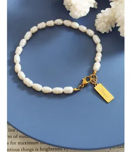 Dettaglio del bracciale di perle con placca rettangolare dorata incisa Love