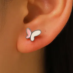 Dettaglio ravvicinato del piercing all'orecchio ad ala di farfalla in smalto rosa e bianco
