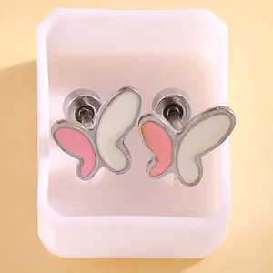 Dettaglio degli orecchini ad ala d'angelo in smalto rosa e bianco con chiusura a vite