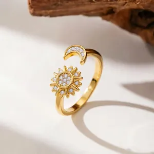 Detailed close-up of golden sun and moon open ring set with sparkling zircons.
