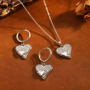 Élégant ensemble de bijoux pendentif coeur argenté avec strass brillants sur fond brun