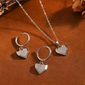 Vue détaillée du collier pendentif cœur et des boucles d'oreilles créoles avec cristaux