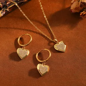 Ensemble de bijoux élégants en cœur doré avec pierres sur fond texturé chaud.