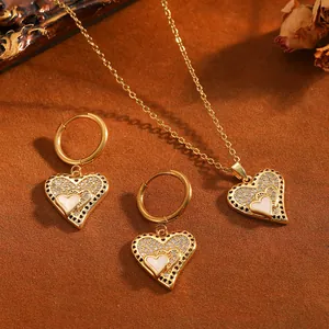 Détail du collier et des boucles d'oreilles cœur dorés avec zircons brillants.