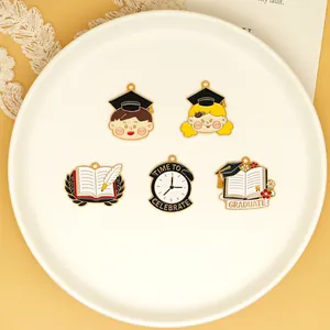 Detail view of five graduation-themed enamel charms on a white decorative plate.