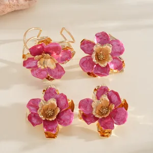 Lot de quatre bagues fleurs plissées rose vif avec élégants anneaux en métal doré style vacances.