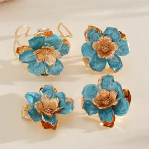 Détails rapprochés de bagues fleur en métal plissé avec finition émail bleu pour femme