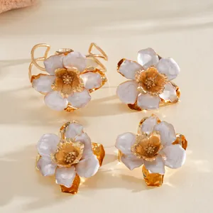 Vue détaillée de bagues élégantes en métal doré avec fleur en émail marbré.