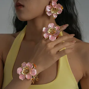 Vue détaillée d'un ensemble de bijoux fleur en émail rose avec accents dorés sur modèle
