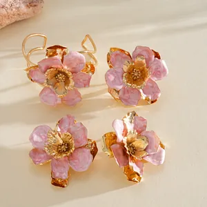 Vue détaillée d'un ensemble de bijoux fleurs en émail rose avec des accents dorés élégants.