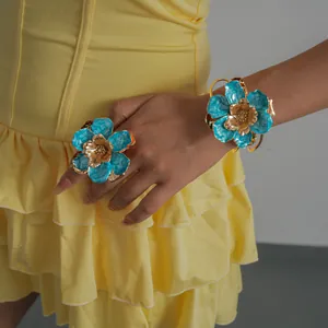 Détail d'un ensemble élégant de bague et bracelet fleur en émail bleu pour femmes.