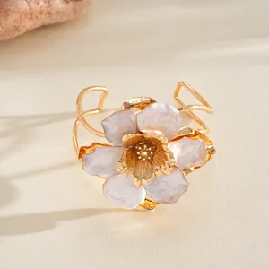 Détail d'une bague fleur dorée avec des pétales en émail irisé et bords ondulés