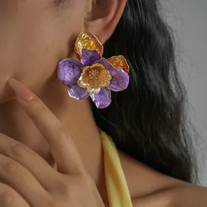 Bijou fleur en émail violet avec des accents dorés, idéal pour un look de vacances chic.