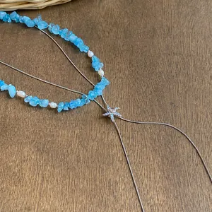 Dettaglio della collana stile oceano con pietre blu, perle e ciondolo a stella marina