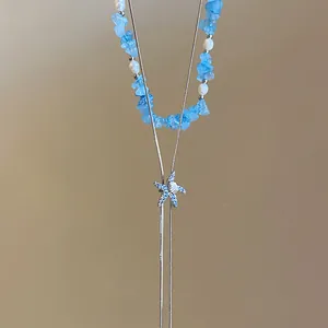 Dettaglio ravvicinato di una collana con ciondolo a stella marina e conchiglia blu con pietre