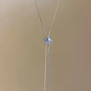 Primo piano di una collana con ciondolo a forma di stella marina blu e conchiglia