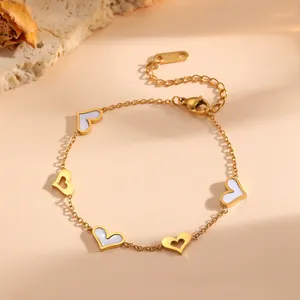 Detalle de una pulsera dorada de acero titanio con corazones de nácar blanco y huecos